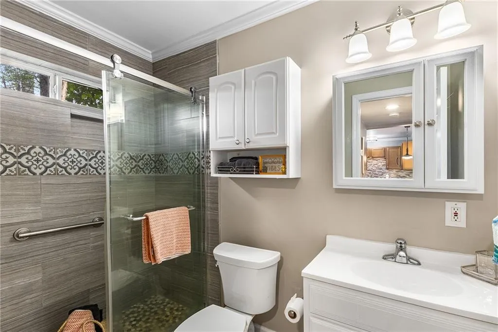 Bathroom with a stall shower, toilet, vanity, and ornamental molding