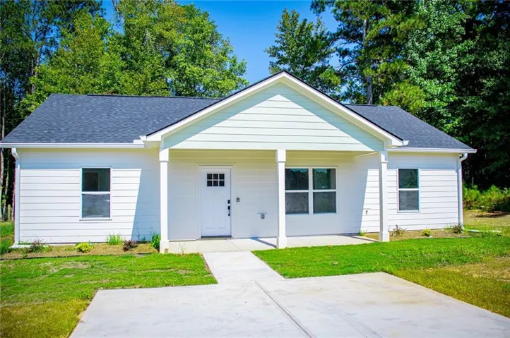 White siding exterior with a dark shingle roof, covered front entry, and a concrete driveway