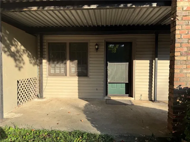 Covered patio area with concrete flooring, supported by dark metal posts and featuring a corrugated metal roof