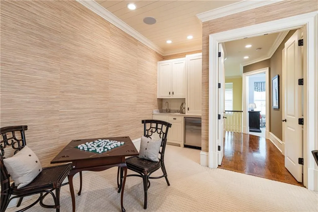 Integrated wet bar with white cabinetry, stainless steel under-counter refrigerator, and built-in sink