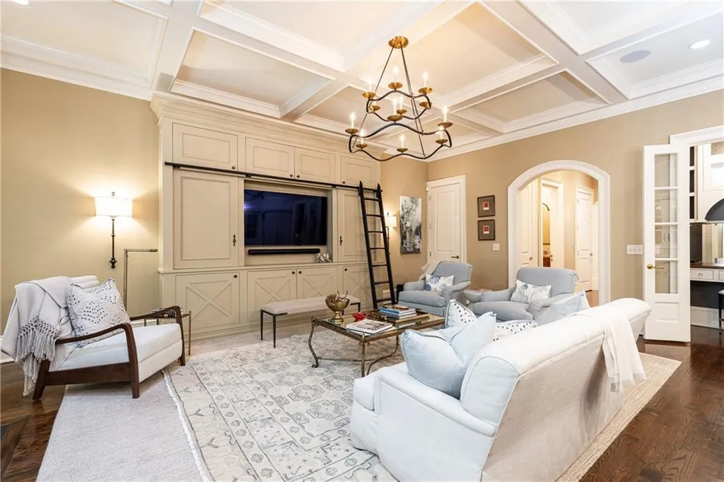 Den features custom built in cabinetry and chandelier