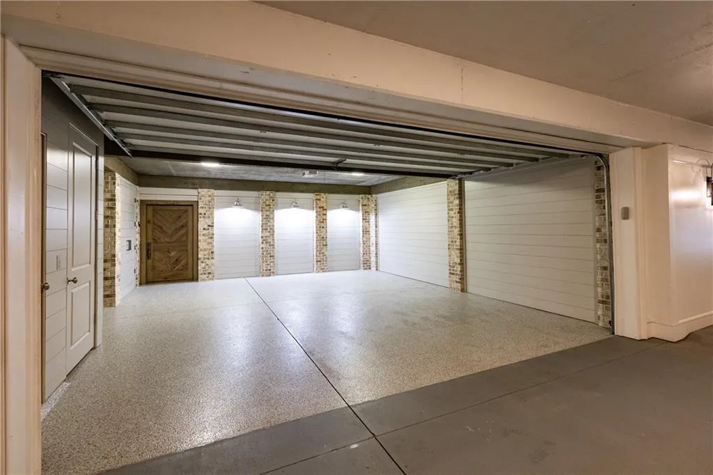 private 2 car garage with shiplap and brick accent walls, sconces, epoxy flooring