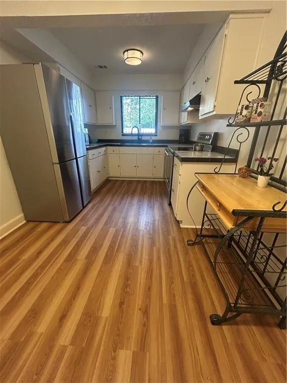 Kitchen with dark countertops, ventilation hood, stove, and fridge