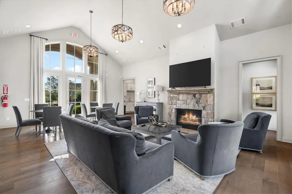 Living room with a chandelier, high vaulted ceiling, wood finished floors, recessed lighting, and a fireplace