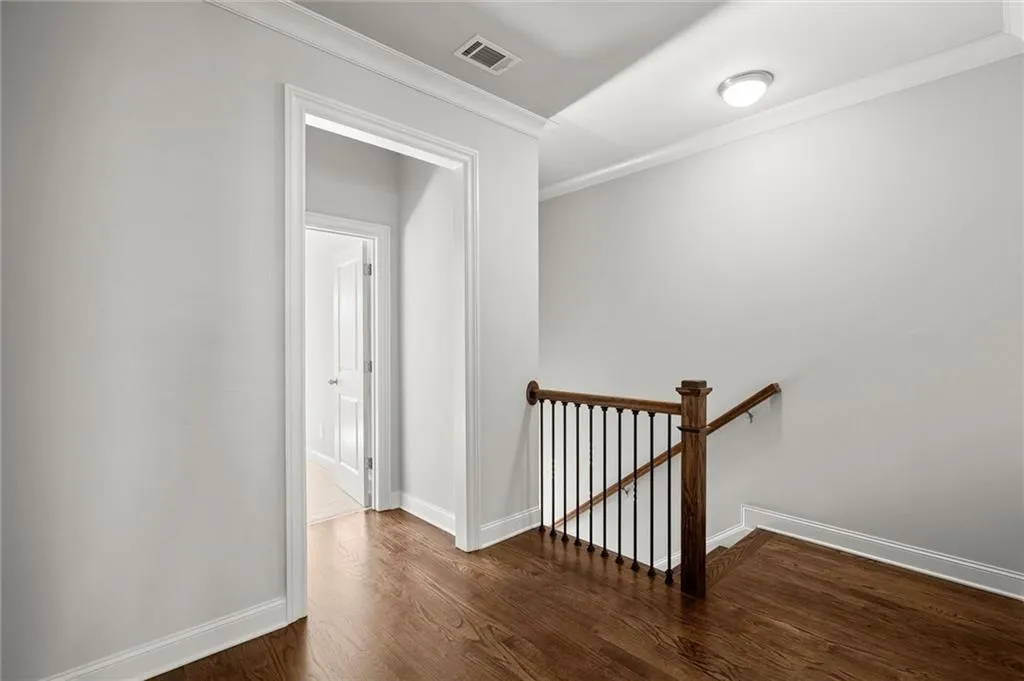 Corridor featuring an upstairs landing, ornamental molding, and dark wood-style floors
