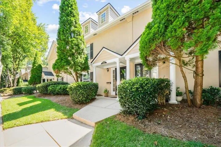 Siding exterior with dormer windows, covered entry, manicured landscaping, and concrete pathway