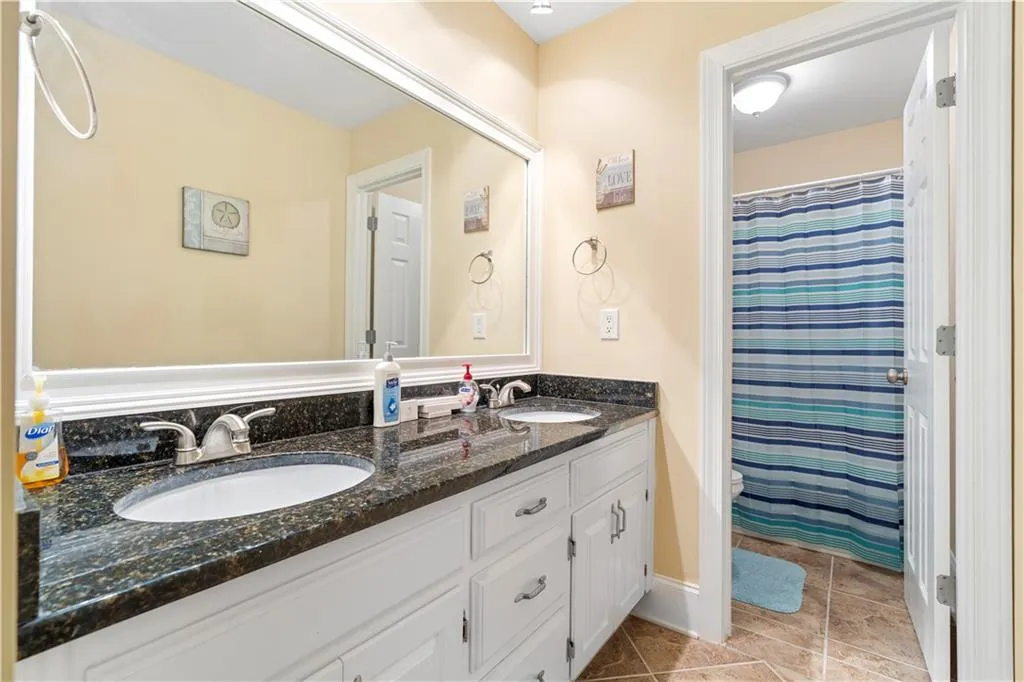 Full bath featuring a shower with curtain, double vanity, and light tile patterned floors