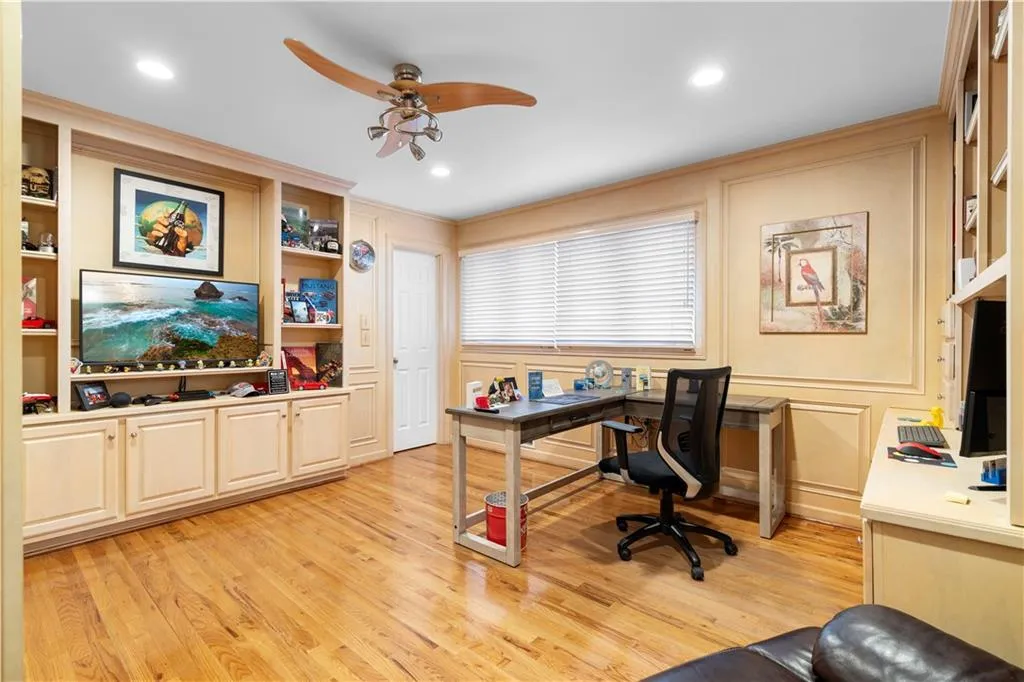 Secondary Bedroom on Main Level used as Office area with a ceiling fan, built in features, light wood-style floors, a decorative wall, and crown molding