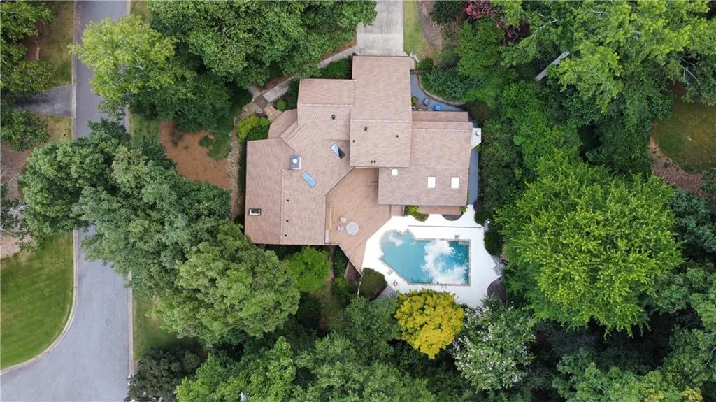 Aerial view of property and surrounding area featuring a pool and a tree filled landscape