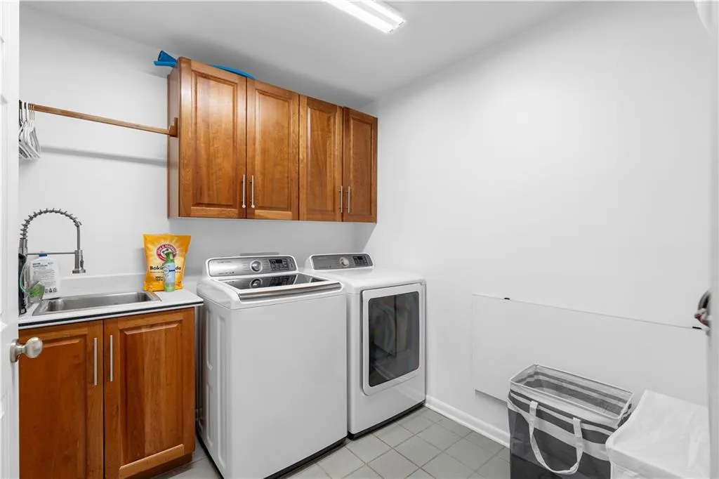 Laundry area featuring washer and clothes dryer, cabinet space, and light tile patterned flooring