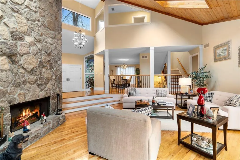 Living room featuring hanging lights, a fireplace, hardwood finished floors, and lofted ceiling