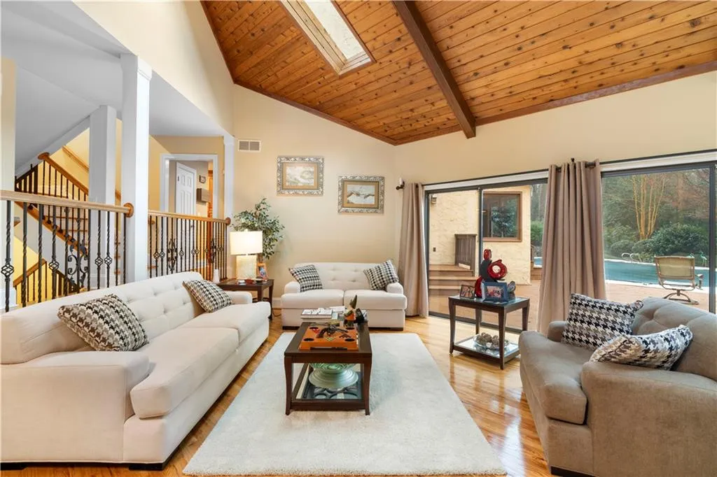 Living room featuring hardwood finished floors, a skylight, and a vaulted wooden ceiling