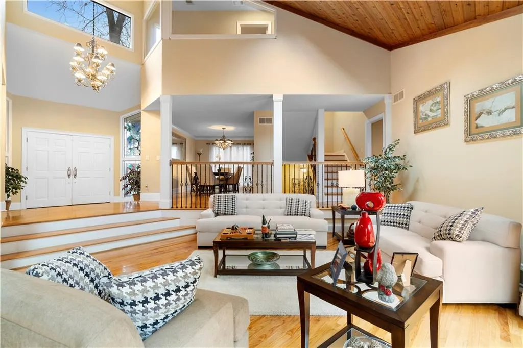 Living room featuring hanging lights, wood finished floors, crown molding, and a high ceiling