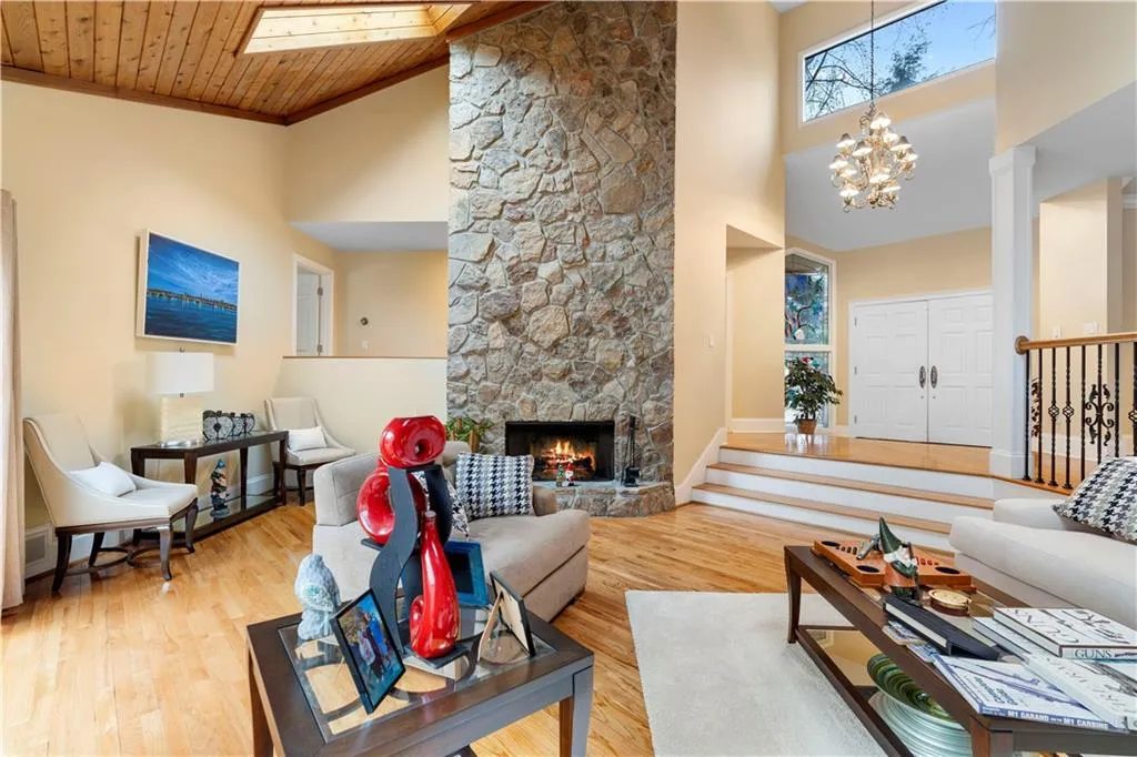 Living room with wood finished floors, a chandelier, a fireplace, a vaulted wood ceiling, and a skylight
