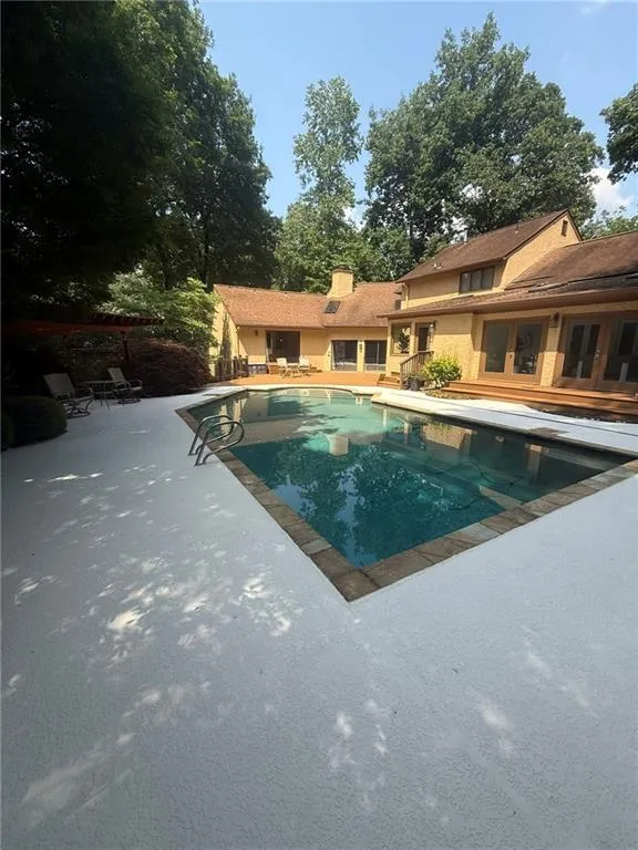 Swimming pool with a patio area and french doors