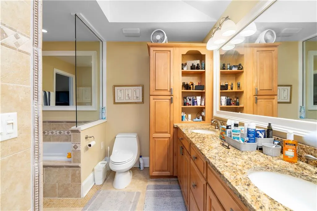 Full bathroom with double vanity, a relaxing tiled tub, and light tile patterned flooring
