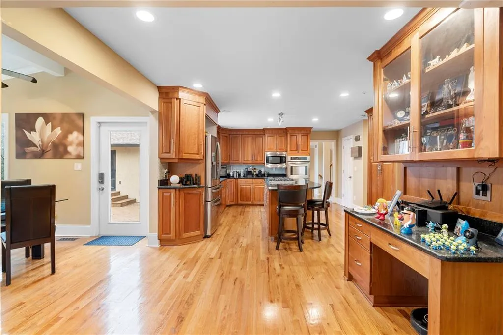 Kitchen featuring glass insert cabinets, a kitchen bar, wood finish cabinetry, light wood-style flooring, and dark stone counters