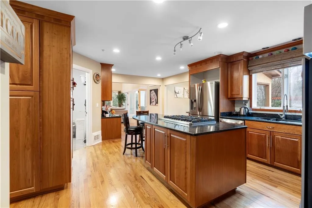 Kitchen with wood finish cabinets, a center island, stainless steel appliances, dark stone counters, and light wood-style flooring