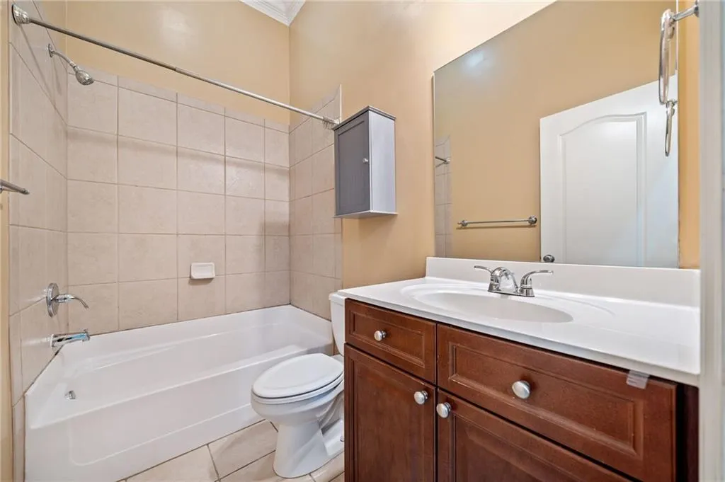 Lower Level Full bath with shower / bath combination, vanity, toilet, tile patterned floors, and ornamental molding