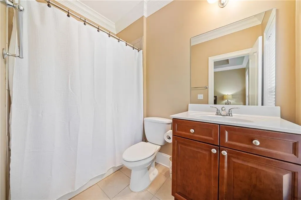 Ensuite Bathroom featuring ornamental molding, toilet, vanity, tile patterned flooring, and a shower with curtain