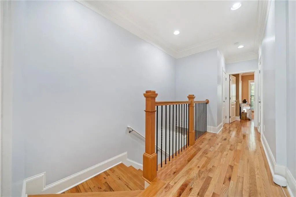 Corridor with an upstairs landing, crown molding, light wood finished floors, recessed lighting, and baseboards