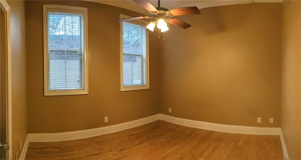 Spare room with wood finished floors, baseboards, and ceiling fan