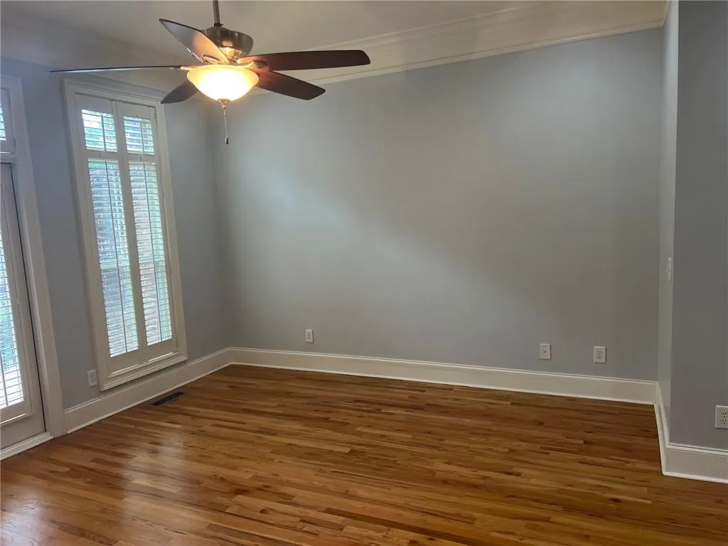 Now empty, Living room or dining room featuring crown molding, wood finished floors, baseboards, and ceiling fan
