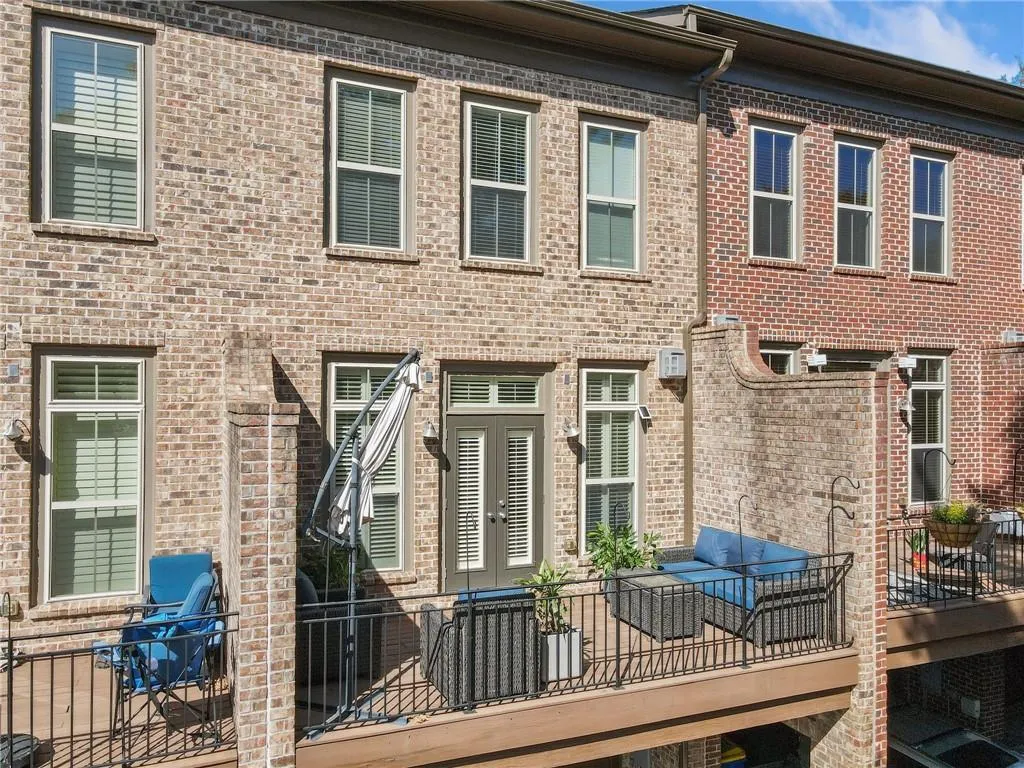 Back of house with brick siding and a balcony