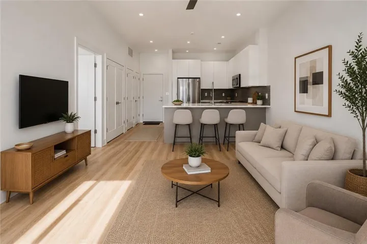 Bright open concept living area with high ceilings, abundant natural light, and seamless connection to the kitchen in this modern Moreland Walk condo. Virtually staged.