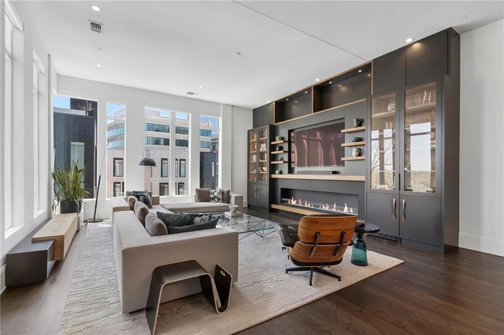 Living room with wood finished floors, a glass covered fireplace, baseboards, visible vents, and recessed lighting