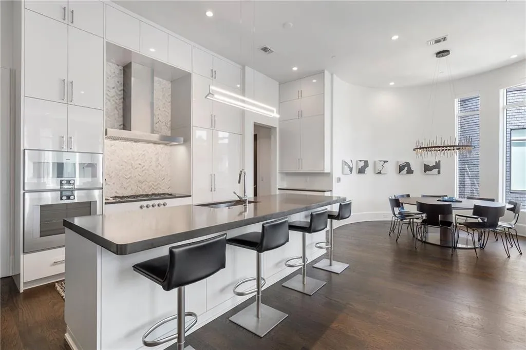 Kitchen featuring visible vents, modern cabinets, wall chimney exhaust hood, dark wood-type flooring, and a sink