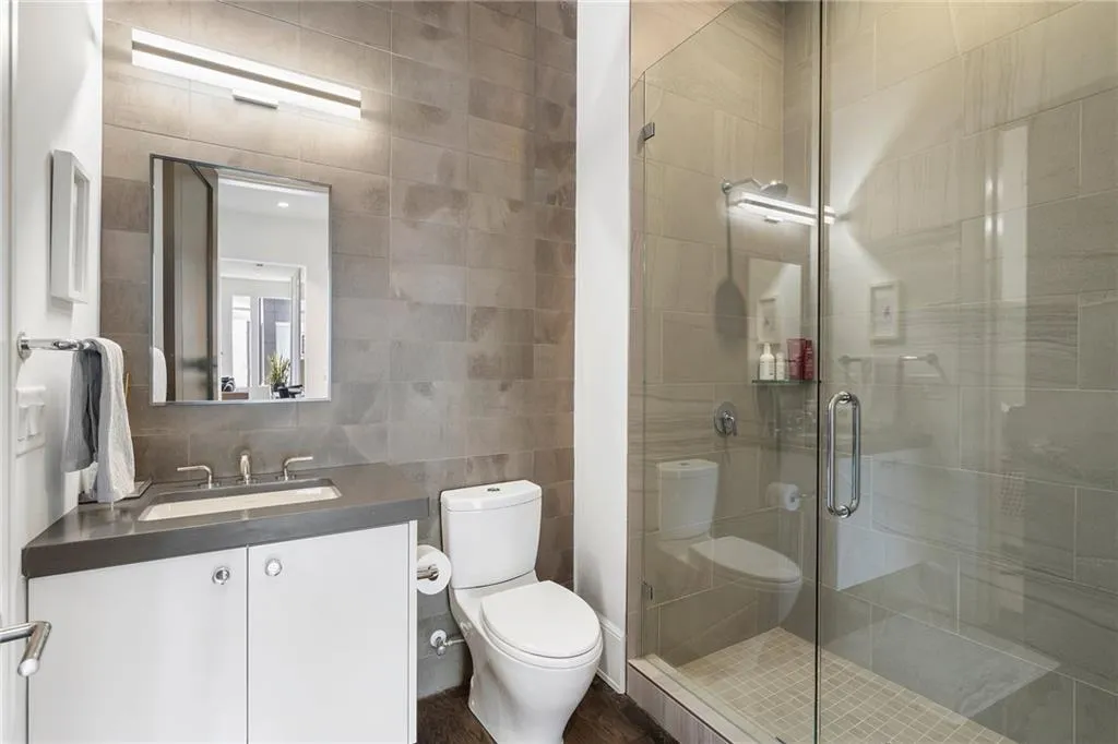 Bathroom featuring vanity, tasteful backsplash, tile walls, toilet, and a stall shower