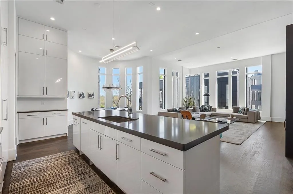 Kitchen with a center island with sink, a sink, dark countertops, and dark wood finished floors