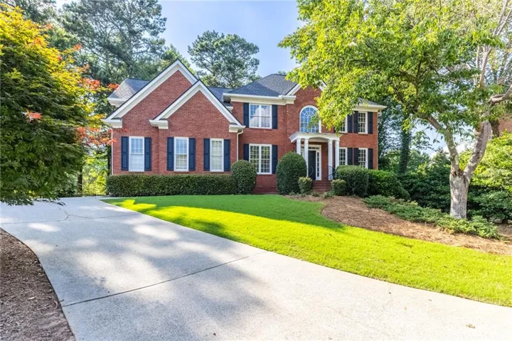 Traditional brick exterior featuring a covered portico entry with columns, multiple gables, and a concrete driveway