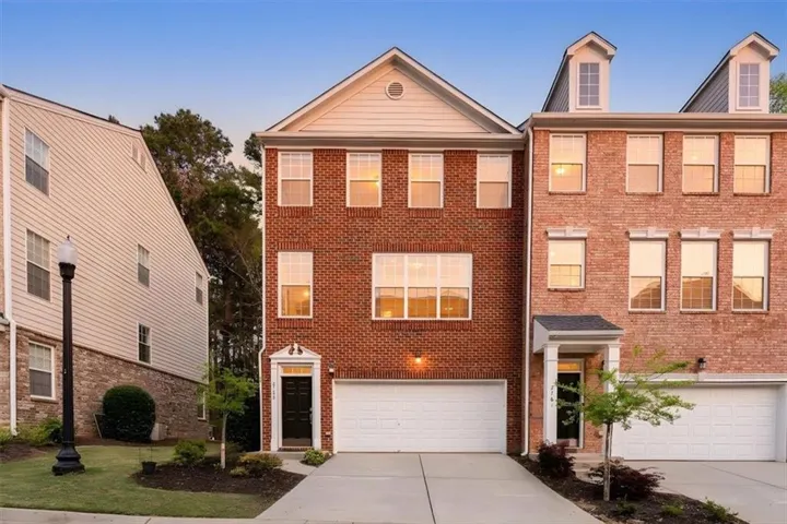 Brick exterior, multiple windows, attached garage, covered entryway, mature landscaping