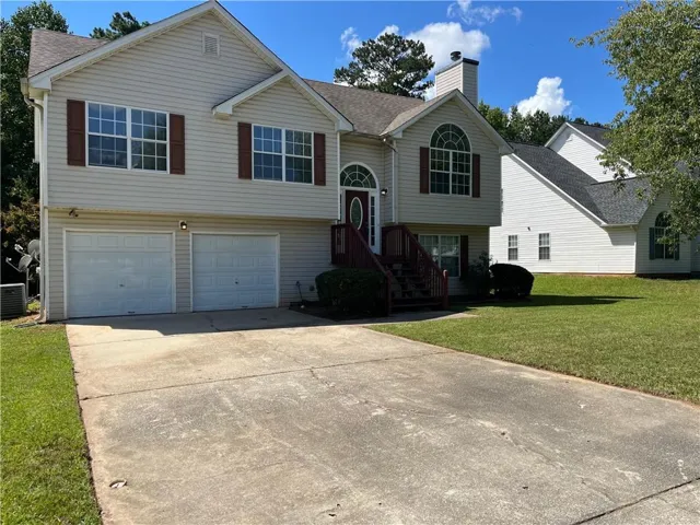 Split-level residence featuring a two-car garage, concrete driveway, and a front entry with a transom window