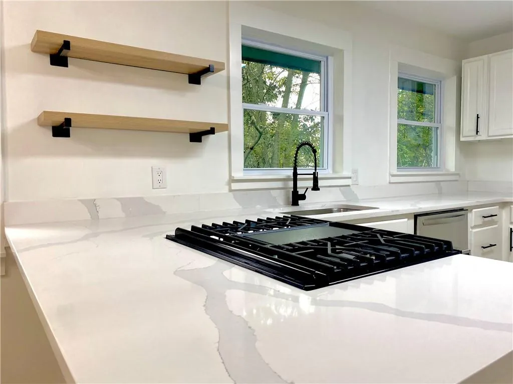 Kitchen featuring light stone counters, white cabinets, black gas stovetop, and plenty of natural light Kitchen featuring light stone counters, white cabinets, black gas stovetop, and plenty of natural light