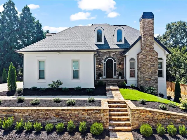 Stucco exterior with stone accents, stone chimney, and arched entry