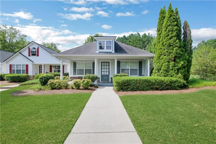 Front exterior featuring a dormer window, covered porch, and mature landscaping