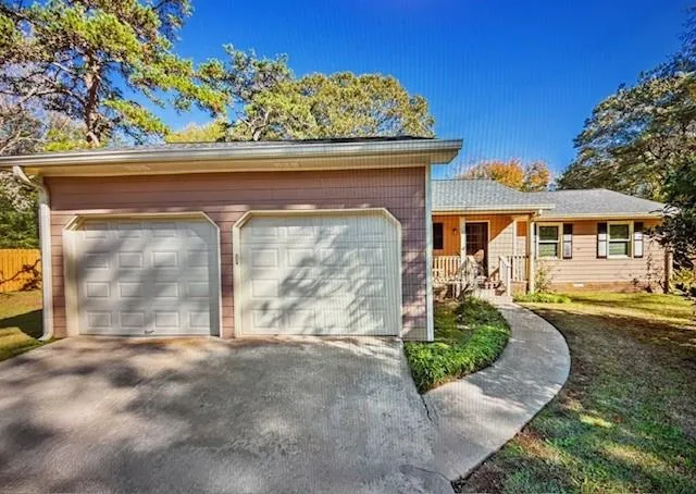 View of front facade featuring driveway, covered porch, an attached garage, and a front yard
