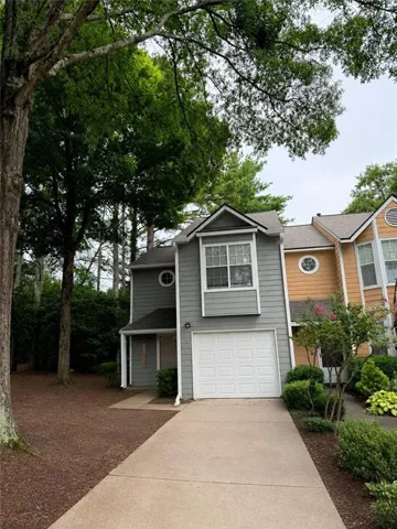 Two-story townhome featuring gray siding, a white garage door, and a concrete driveway