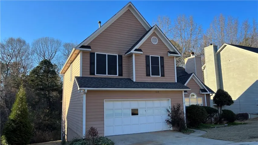 Two-story residence featuring light brown siding and a two-car garage