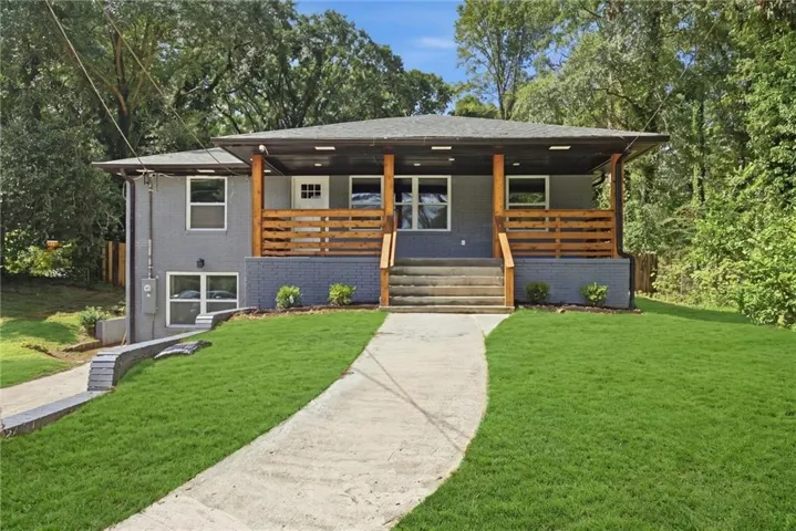 Modern exterior with gray siding, wood-toned porch railings, a covered entry, and a concrete pathway
