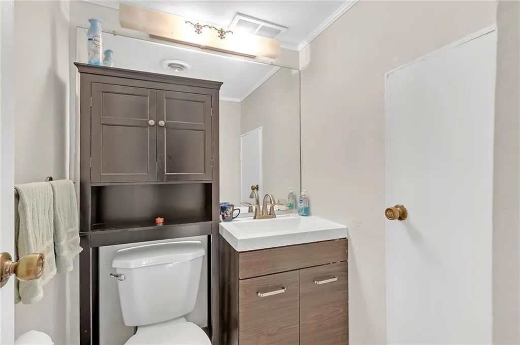 Half bathroom with vanity and ornamental molding