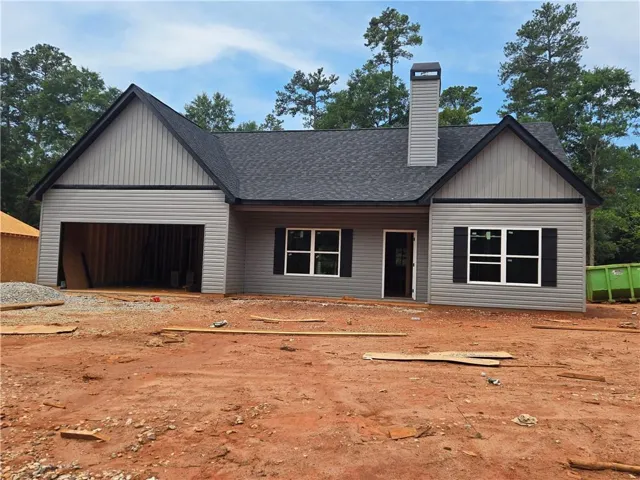 Newly constructed single-story residence featuring grey siding, a dark shingle roof, and a prominent chimney