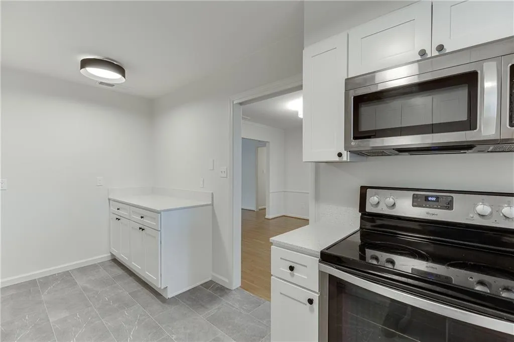 Kitchen featuring baseboards, light countertops, white cabinets, and appliances with stainless steel finishes