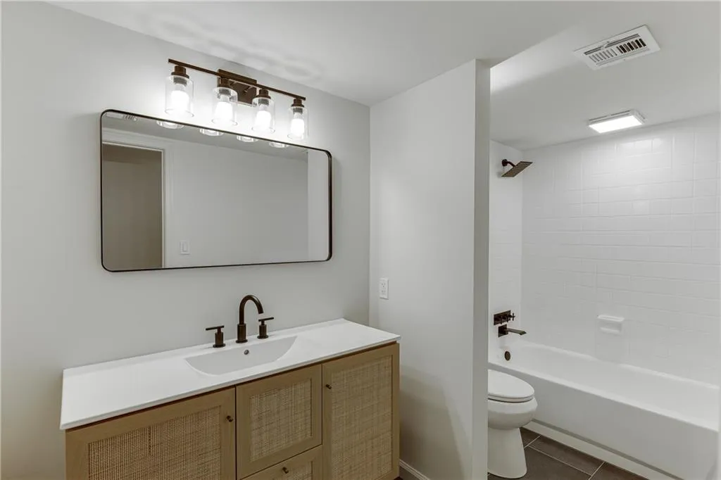 Full bathroom with tile patterned floors, bathtub / shower combination, toilet, vanity, and visible vents