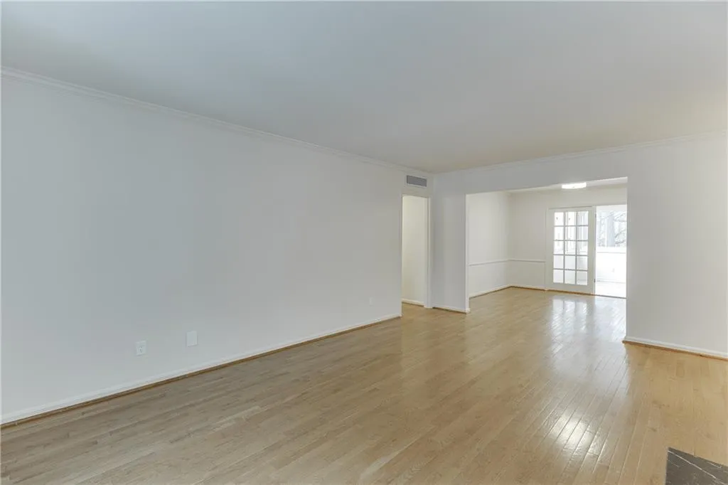 Empty room featuring baseboards, visible vents, ornamental molding, and light wood-style flooring