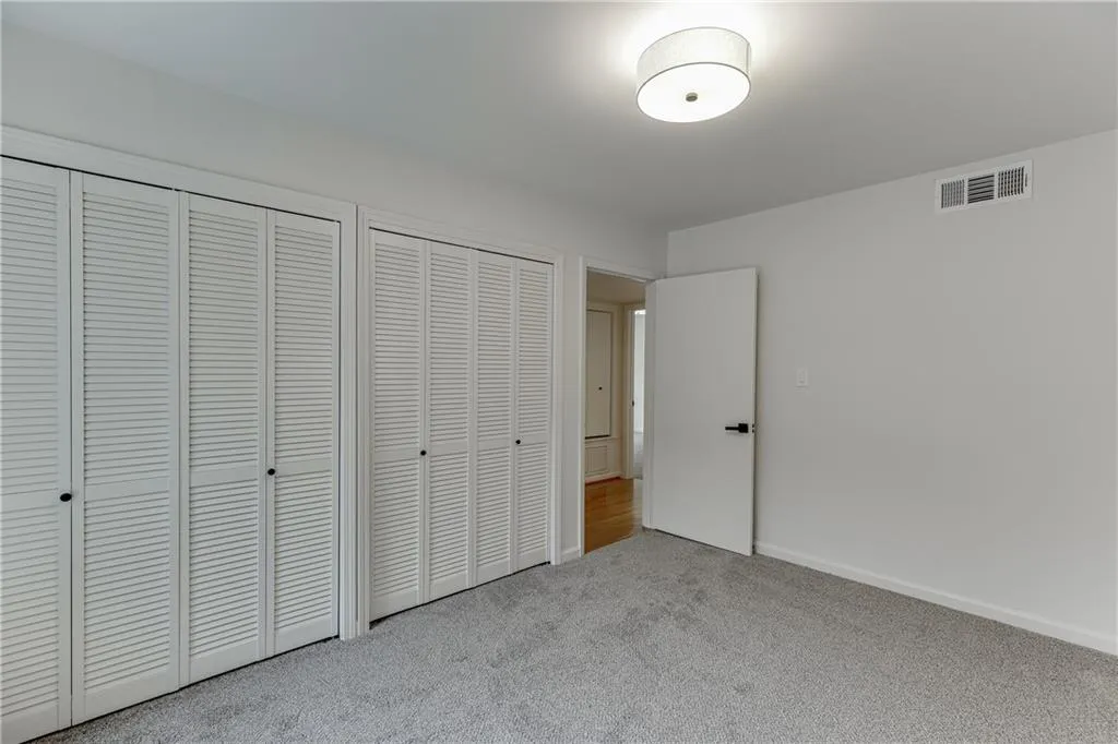 Unfurnished bedroom with two closets, carpet floors, baseboards, and visible vents