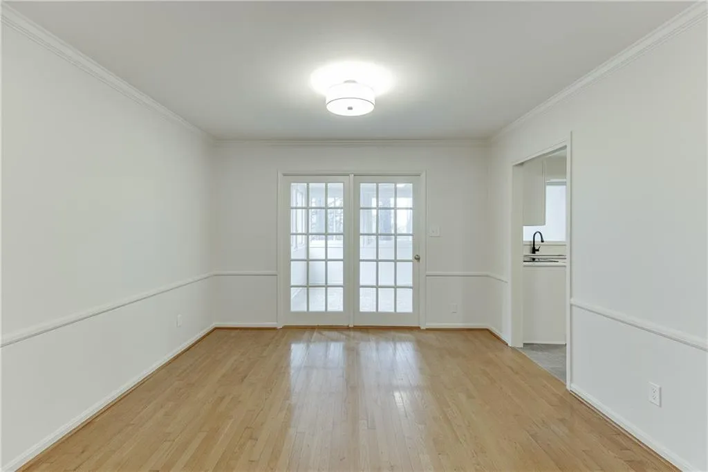 Spare room with baseboards, a sink, light wood-style floors, and crown molding